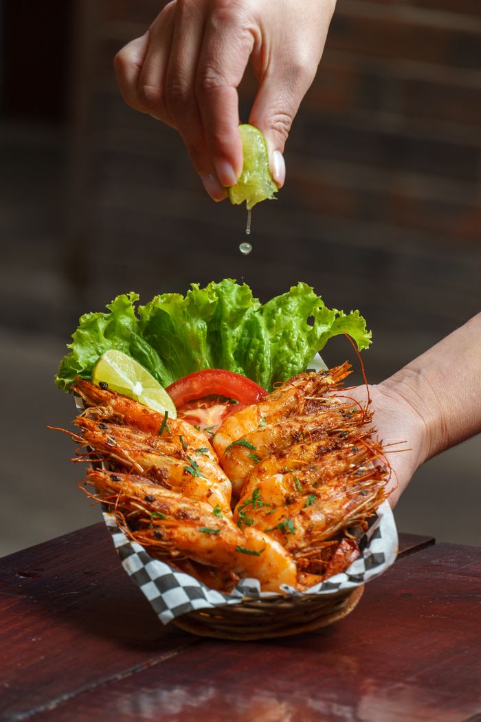 Delicious grilled shrimp garnished with lime and fresh lettuce, perfect for a seafood meal.